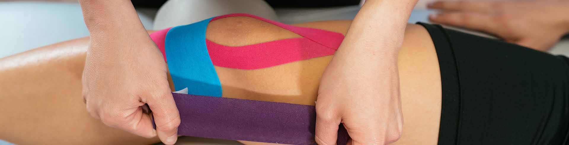 Rehab Specialist Applying Kinesiology Tape Over Patient's Knee